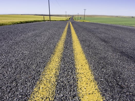 Rural road with double yellow lines through slightly rolling farmland west of The Palouse region in eastern Washington, USA, on a morning early in summer